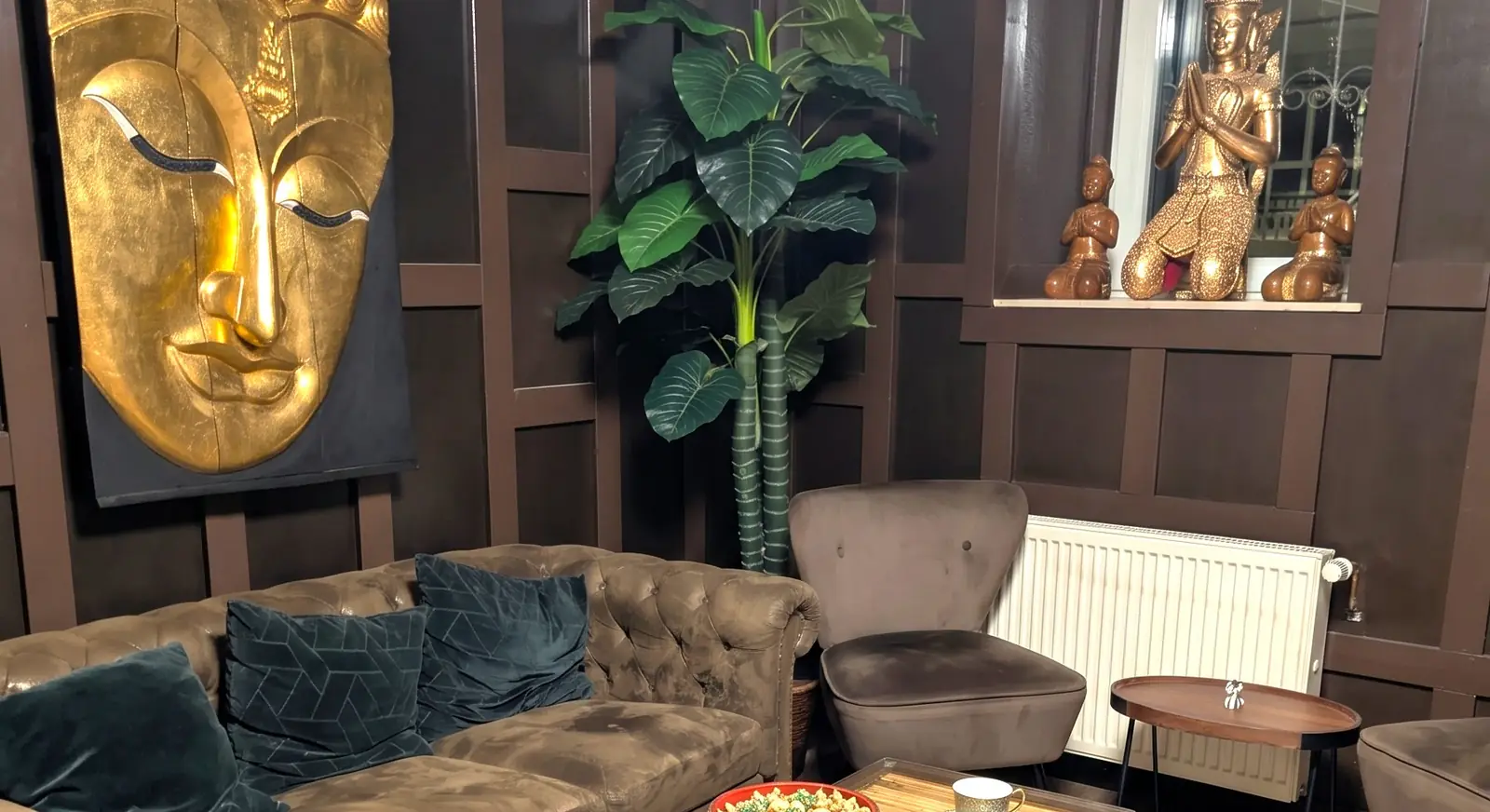 Warteecke mit Sofa, Sessel und goldener Buddha-Figur